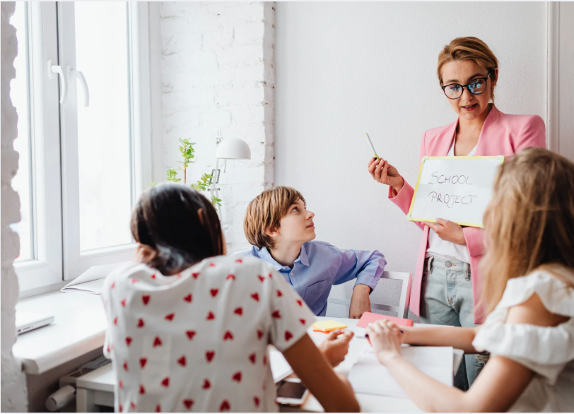 A teacher with yound students in a classroom