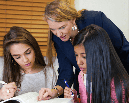 A teacher guiding two elementary leaners
